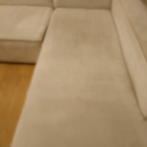 ספה בהירה עם כריות על רצפת עץ