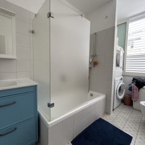 חדר אמבטיה עם מקלחון, ארון כחול ומכונת כביסה