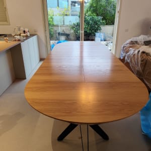 שולחן עץ בחדר עם חלון גדול וגינה בחוץ