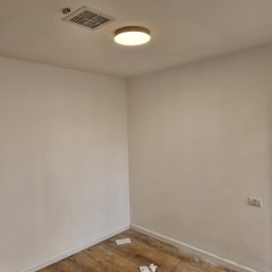 חדר צבוע עם קירות לבנים וכלי צבע על הרצפה