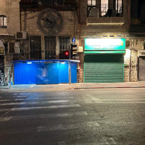 קיר עם גרפיטי וסולם ליד חנות סגורה בלילה