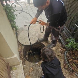 עובד משתמש בצינור לניקוי בור ביוב