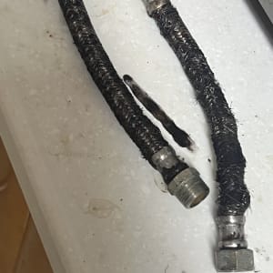 שני צינורות גומי עם חיבורים מתכתיים על משטח לבן