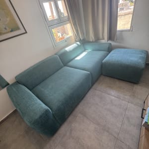 ספה ירוקה ליד חלון עם וילון פתוח