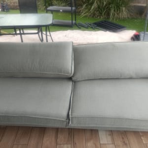 ספה אפורה על רצפת עץ בגינה