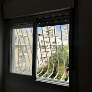 חלון עם סורגים ונוף עירוני ברקע