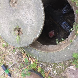 פתח ביוב עם כלי עבודה ונעל על הקרקע