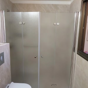 חדר אמבטיה עם מקלחון ודלת זכוכית