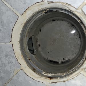 פתח ניקוז עם סימני חלודה ומים עומדים