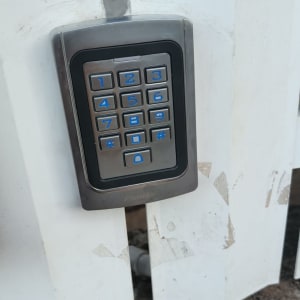 לוח מקשים מתכת על גדר לבנה