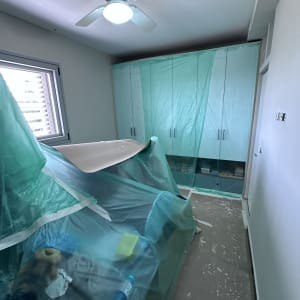 חדר עם רהיטים מכוסים בניילון לקראת צביעה