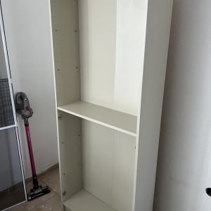 ארון לבן ריק ליד שואב אבק על רצפה