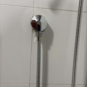 צינור מקלחת מחובר לקיר עם אריחים לבנים