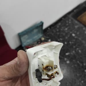 שקע חשמלי מפורק עם חוטים חשופים ביד חשמלאי