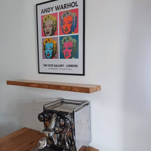 מכונת אספרסו על מדף עץ מתחת לפוסטר