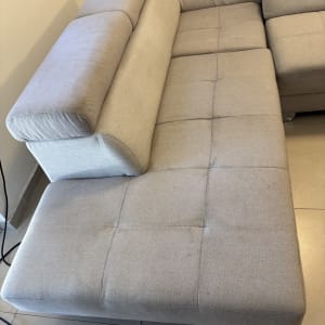 ספה בהירה עם כתמים קלים על הרצפה