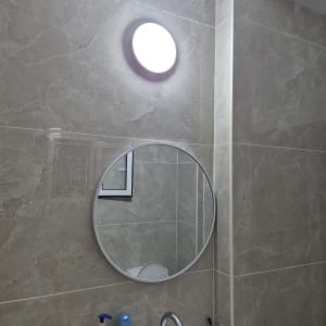 מראה עגולה בחדר אמבטיה עם תאורה עליונה