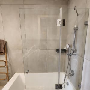 אמבטיה עם דלת זכוכית, ראש מקלחת וצינור מתכת