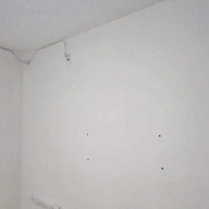 קיר צבוע בלבן עם חורים קטנים ושקעי חשמל