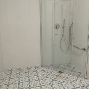 מקלחון זכוכית עם אריחים מעוצבים על הרצפה