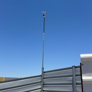 מצלמת אבטחה מותקנת על עמוד גבוה ליד גדר מתכת