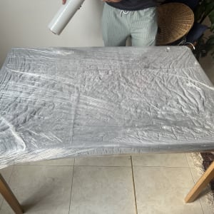שולחן עטוף בניילון עם אדם מחזיק גליל