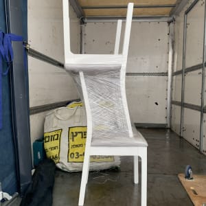כיסאות לבנים עטופים בניילון בתוך משאית הובלה
