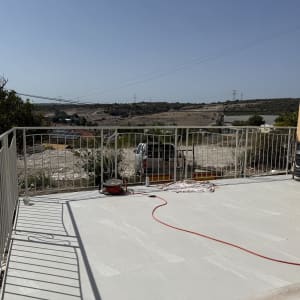 מעקה ממתכת לבן המותקן בהיקף מרפסת מרוצפת