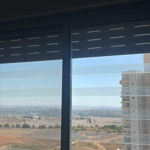 תריס גלילה ורשת בחלון הזזה אלומיניום עם נוף עירוני