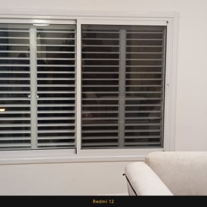 תריסים לבנים על חלון קיר פנימי