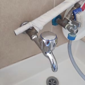 ברז כרום עם צינורות מחוברים ועטופים בסרט לבן