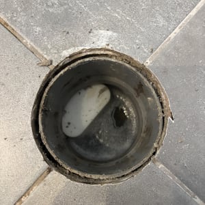 צינור פתוח עם מים על רצפה אפורה