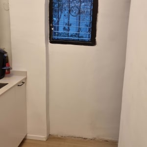 קיר צבוע מחדש עם חלון קטן ורצפת עץ חדשה