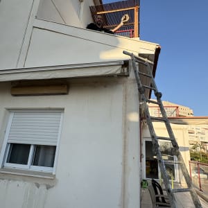 אדם על מרפסת עם סולם, מחזיק קן צרעות