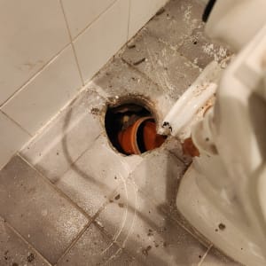 צינור כתום חשוף ברצפת חדר אמבטיה