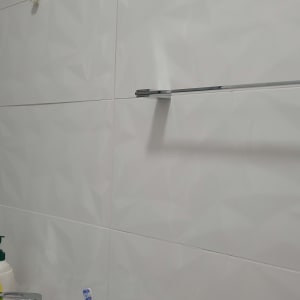 מוט מגבת מתכת מותקן על קיר אריחים לבן