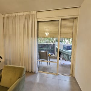 תריסים וחלון זכוכית בסלון עם וילון לבן