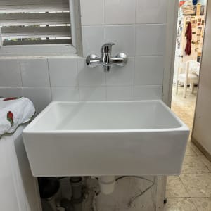 כיור לבן עם ברז כרום מותקן על קיר אריחים