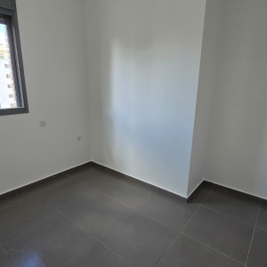 קיר צבוע בלבן בחדר ריק עם רצפת אריחים אפורה