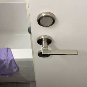 ידית דלת מתכתית על דלת לבנה בחדר אמבטיה