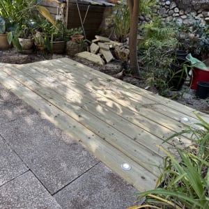 דק עץ מותקן בגינה עם צמחים מסביב