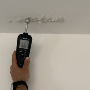 מד לחות נוגע בתקרה עם סימני רטיבות