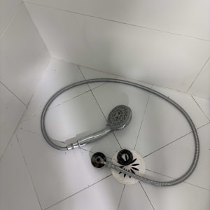 ראש מקלחת וצינור על רצפת מקלחת