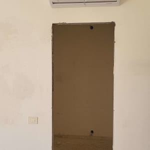 מזגן מותקן על קיר בחדר ריק עם חוטים חשופים