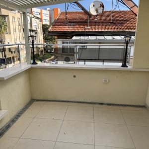 מרפסת עם מעקה זכוכית ונוף לבניינים