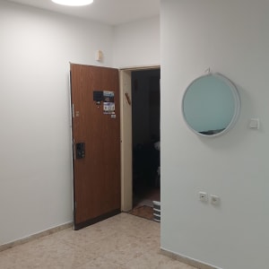 קיר צבוע עם מראה עגולה ודלת עץ