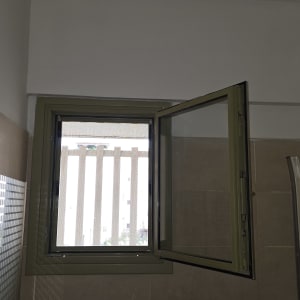 חלון פתוח עם מסגרת מתכת וקיר אריחים