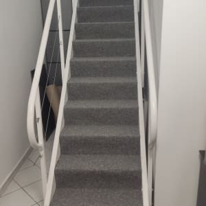 גרם מדרגות עם שטיח אפור ומעקה לבן