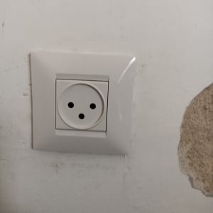 שקע חשמל בקיר עם סימני תיקון