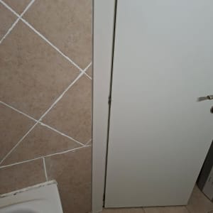 דלת וחלק מקיר עם אריחים בחדר אמבטיה